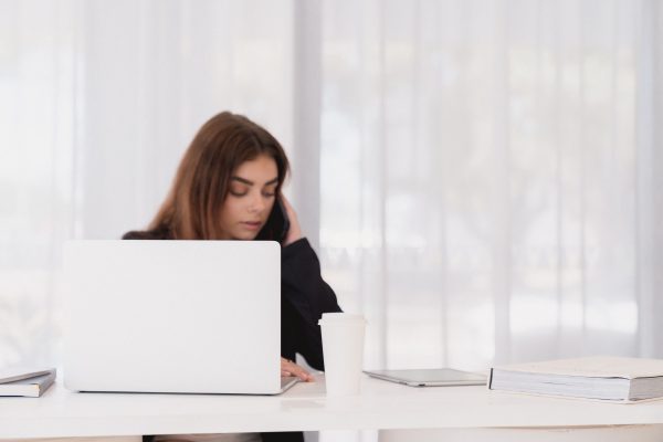 A stock image of business woman sitting at a desk in an all white office space
